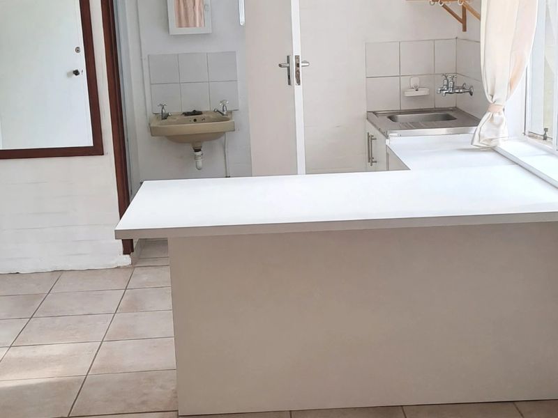 A functional kitchen area featuring a central island, tiled flooring, and a secondary basin, offering a blank canvas for potential modern updates.