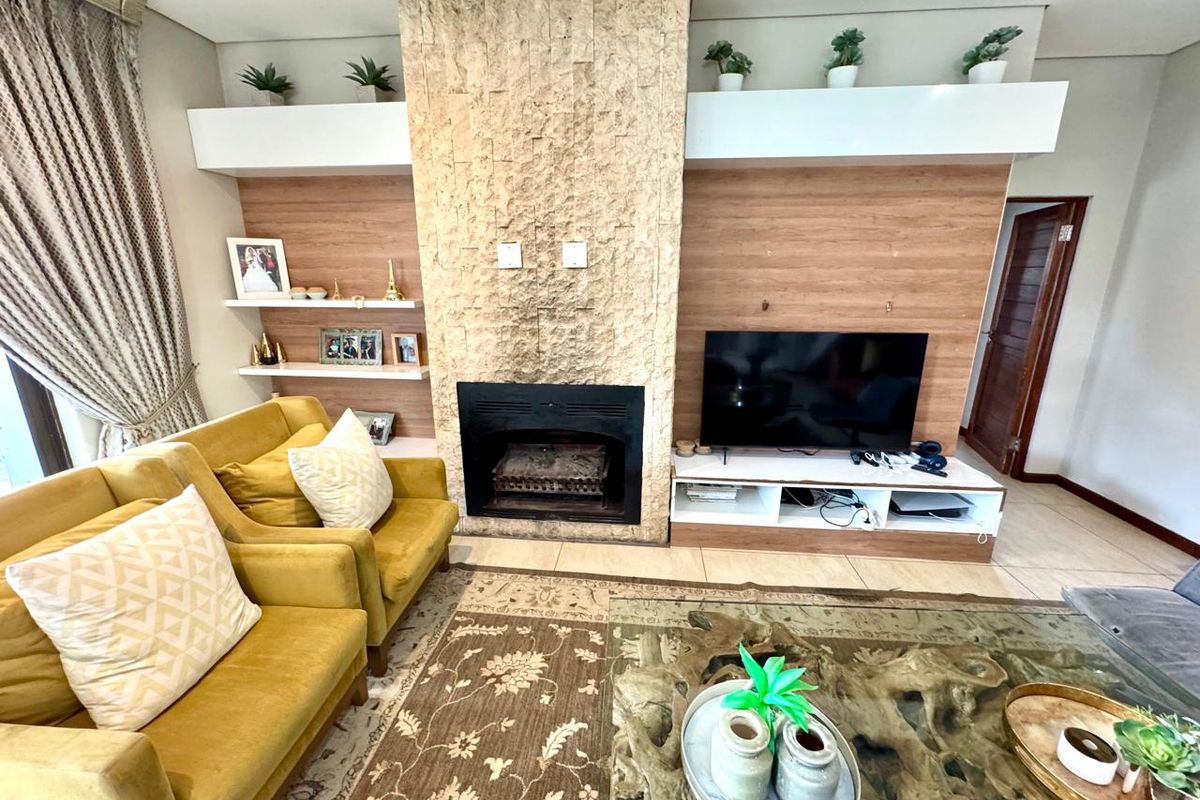 A cozy living room featuring a prominent stone-clad fireplace, built-in wooden cabinetry, and tiled flooring.