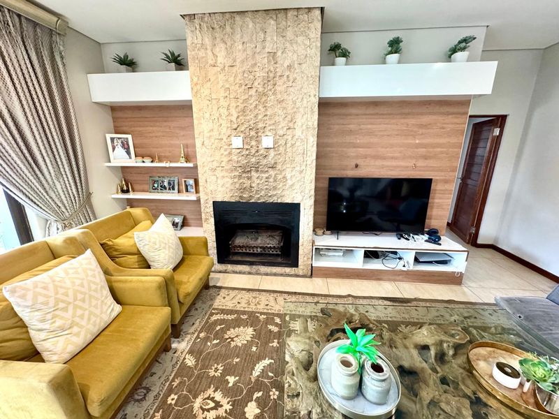 A cozy living room featuring a prominent stone-clad fireplace, built-in wooden cabinetry, and tiled flooring.