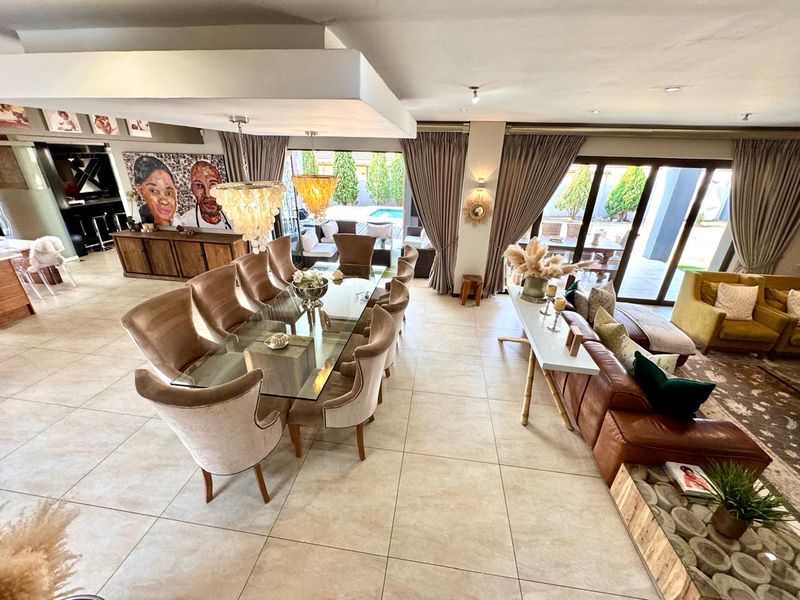 Spacious open-plan living and dining area featuring large format floor tiles, recessed ceiling detail, and expansive sliding doors leading to the outdoor patio.