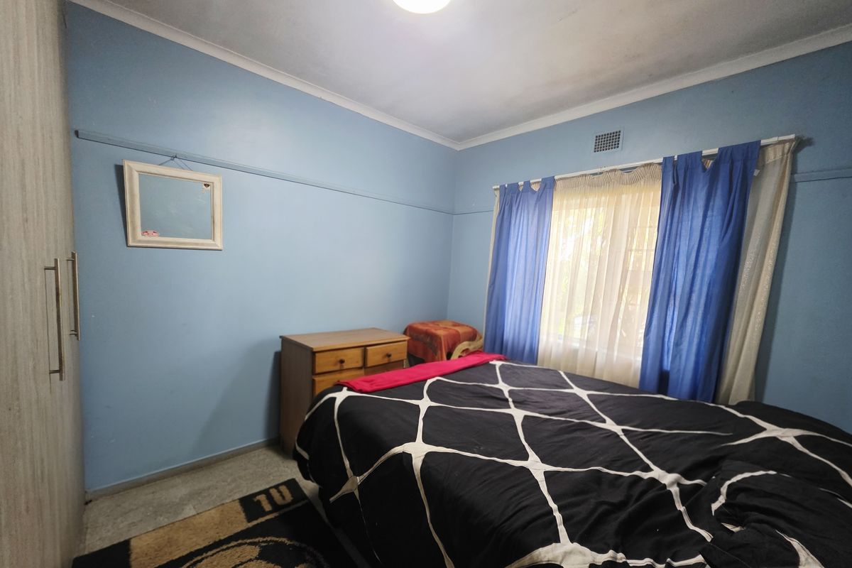 A bedroom featuring blue walls, a built-in wardrobe, and a picture rail, requiring cosmetic updates to improve its overall appeal.