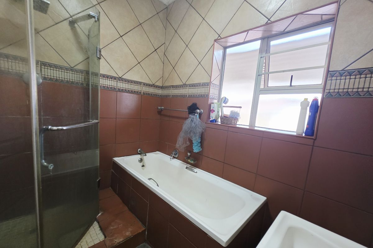 Bathroom featuring a built-in bathtub, separate glass-enclosed shower, and full-height tiled walls with a decorative border.