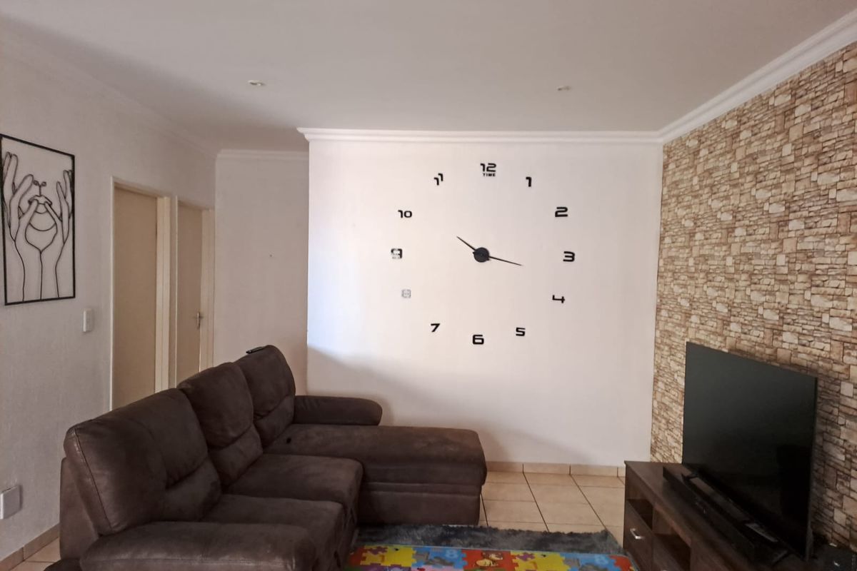 A living room featuring tiled flooring, a stone-effect feature wall, and coving, providing a functional space for relaxation.