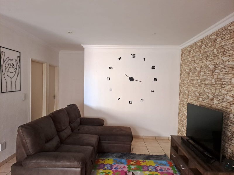 A living room featuring tiled flooring, a stone-effect feature wall, and coving, providing a functional space for relaxation.