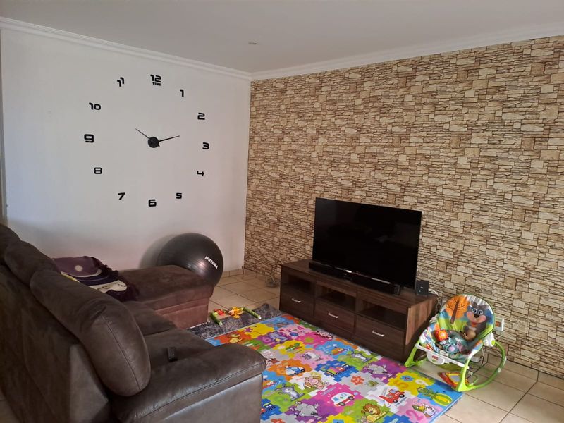 Living room featuring tiled flooring and a textured stone-effect feature wall, providing a neutral base for interior design updates.