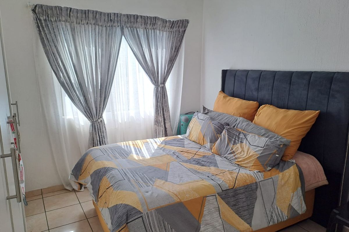 A functional bedroom featuring tiled flooring and a window with installed curtain rails, providing a neutral base for personal styling.