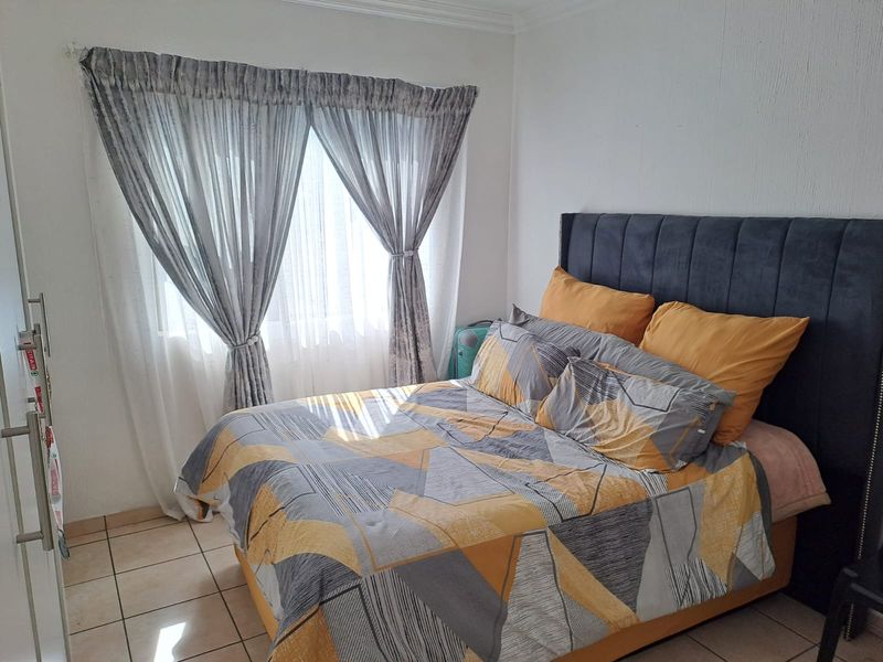 A functional bedroom featuring tiled flooring and a window with installed curtain rails, providing a neutral base for personal styling.