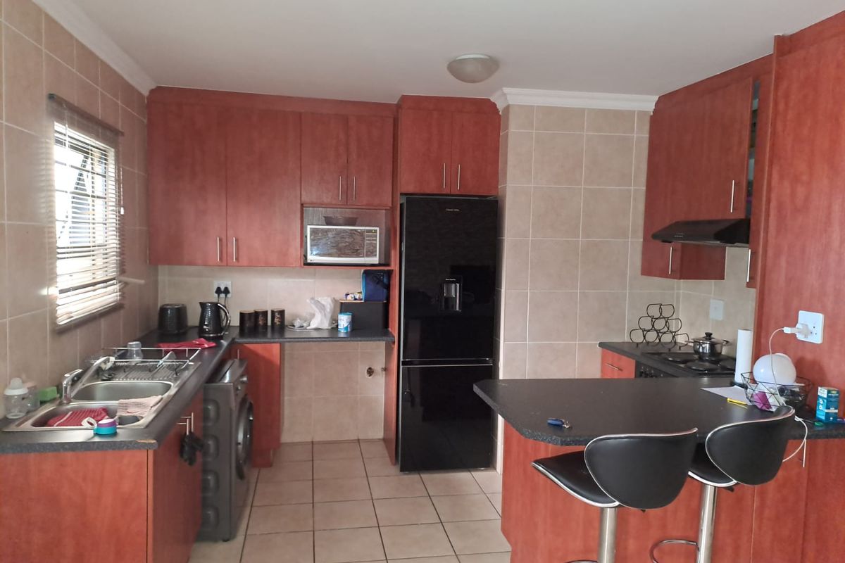 A functional kitchen featuring wood-finish cabinetry, tiled backsplash, a breakfast bar, and integrated appliances, offering a practical layout for daily use.