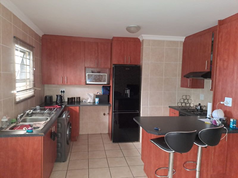 A functional kitchen featuring wood-finish cabinetry, tiled backsplash, a breakfast bar, and integrated appliances, offering a practical layout for daily use.