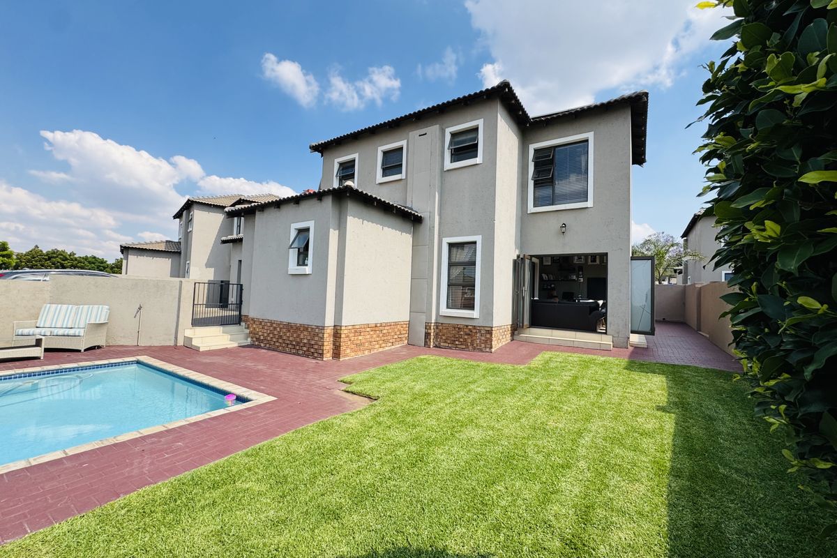Rear view of the townhouse featuring a private swimming pool, paved patio area, and a well-maintained lawn.