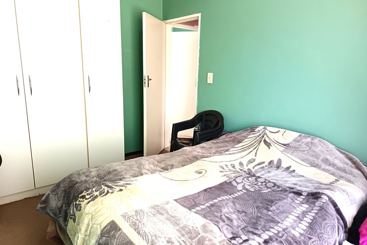 A bedroom featuring a built-in wardrobe and green painted walls, requiring minor repairs to the door frame.