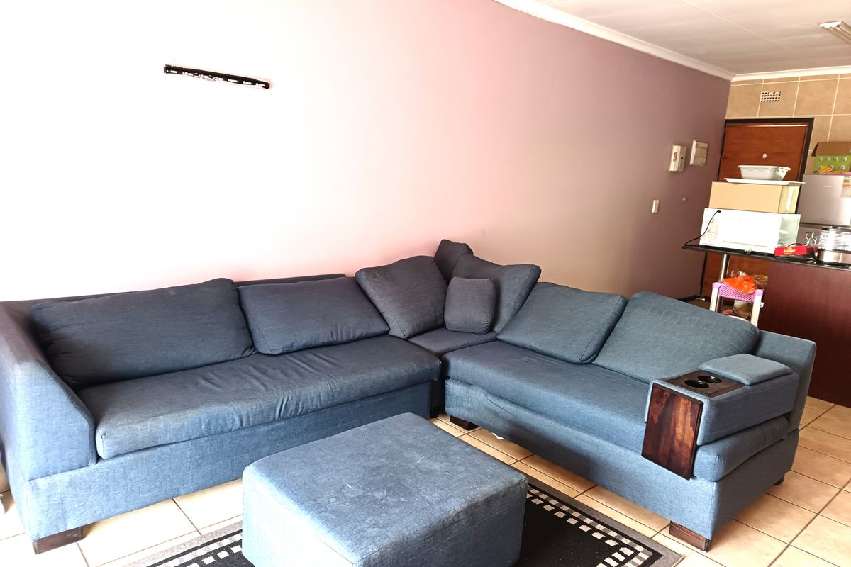 A living room area featuring tiled flooring and a wall-mounted television bracket, providing a functional space for relaxation.