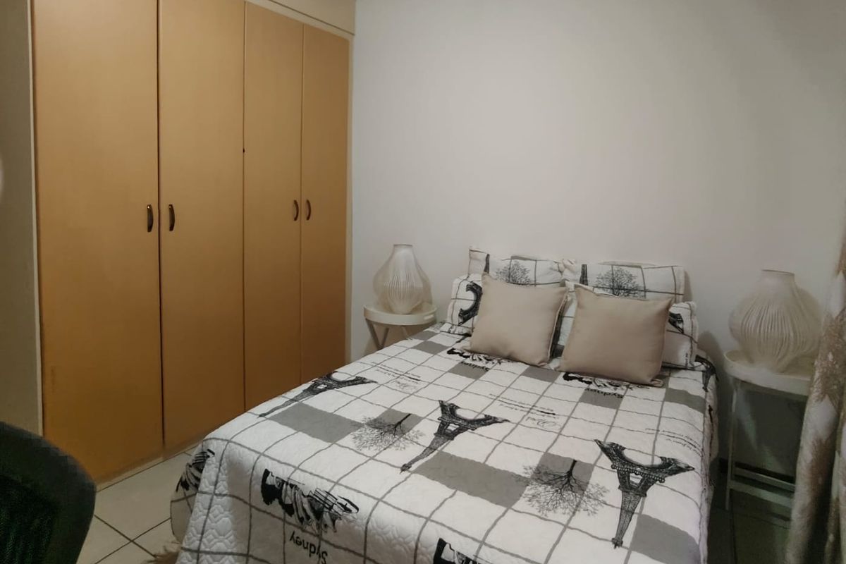 A bedroom featuring built-in wooden wardrobes and tiled flooring.