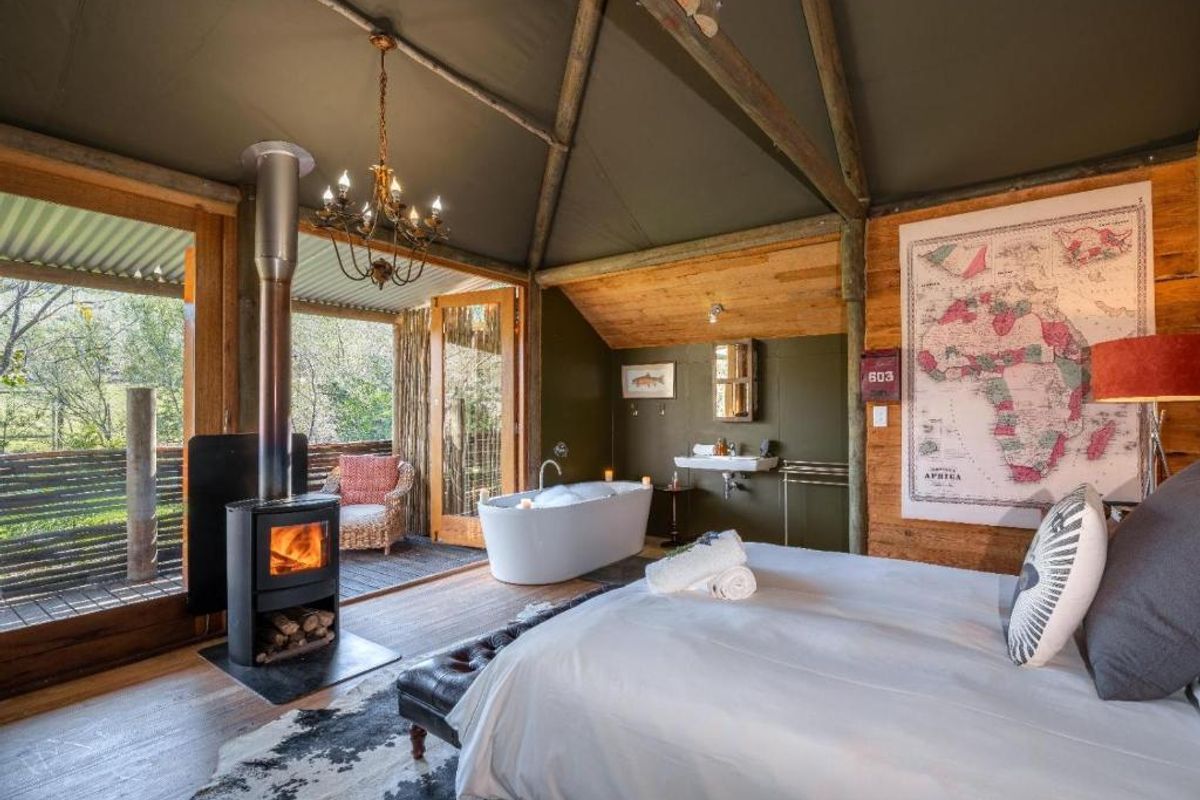 A luxury bedroom suite featuring a freestanding bathtub, wood-burning stove, and direct access to a private timber deck with scenic views.