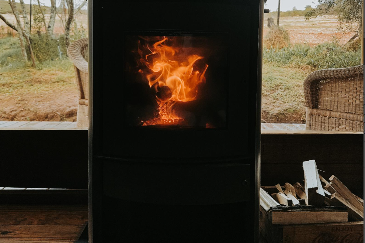 A cozy living space featuring a functional wood-burning stove, providing warmth and a rustic atmosphere with views of the surrounding farm landscape.