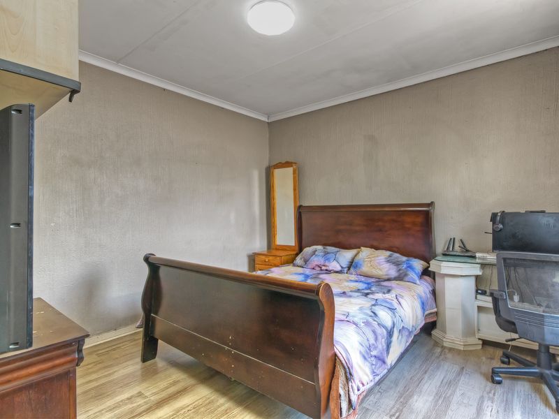 A bedroom featuring laminate flooring and a ceiling-mounted light fixture, with walls showing signs of wear and scuffing.