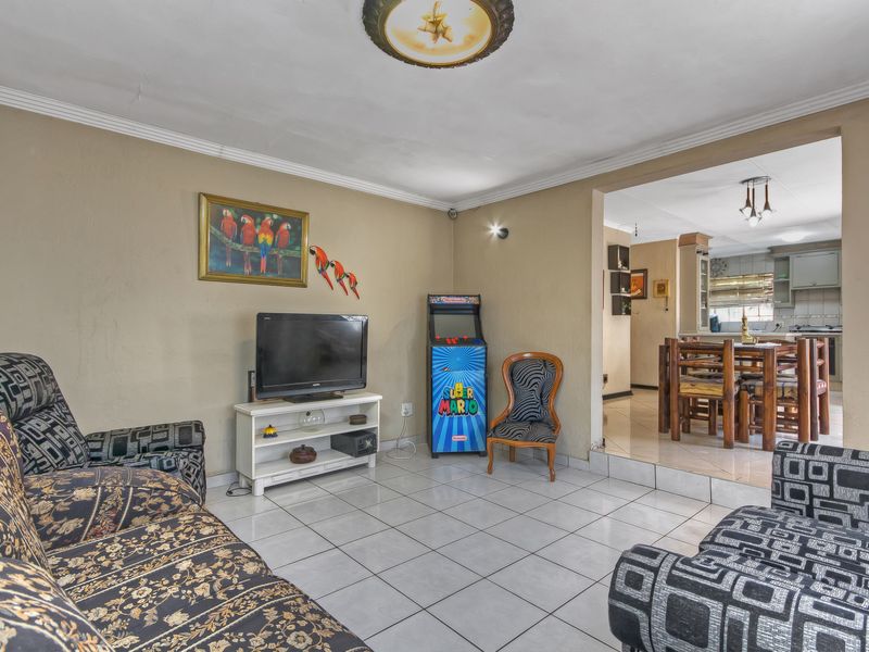 Open plan living area featuring tiled flooring and coved ceilings, with a seamless transition into the adjacent dining and kitchen space.