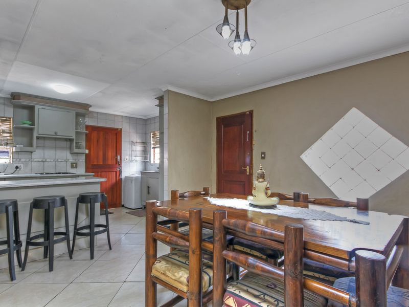 Open plan dining and kitchen area featuring tiled flooring, breakfast bar, and functional cabinetry with integrated cooking appliances.