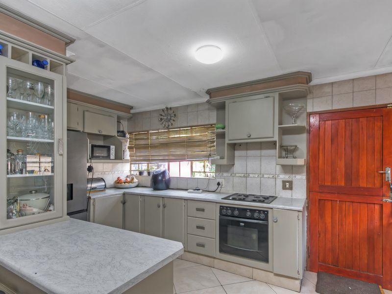 Functional kitchen featuring built-in cabinetry, laminate countertops, integrated oven and hob, and tiled backsplash with direct access to an exterior door.