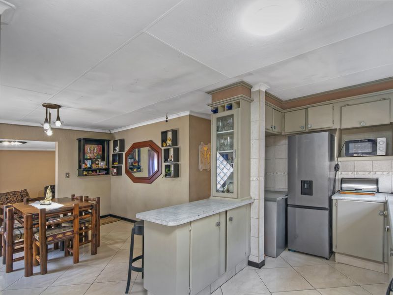 Open plan kitchen and dining area featuring tiled flooring, built-in cabinetry, and a breakfast bar, offering a functional layout for daily living.