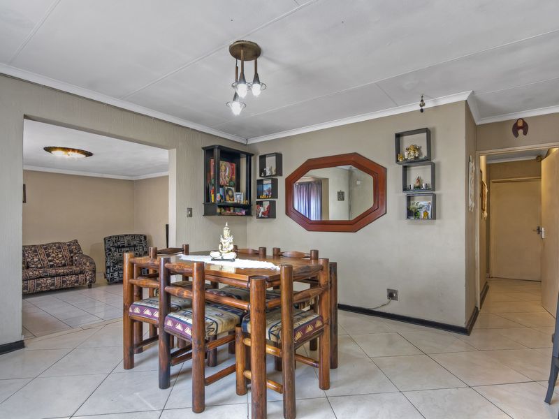 Dining area featuring tiled flooring and neutral wall tones, providing an open-plan flow into the adjacent living space.