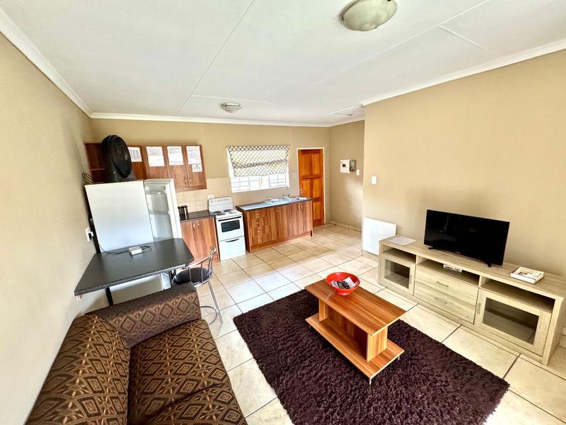 Open-plan living and kitchen area featuring tiled flooring, wooden cabinetry, and a functional layout suitable for modern updates.