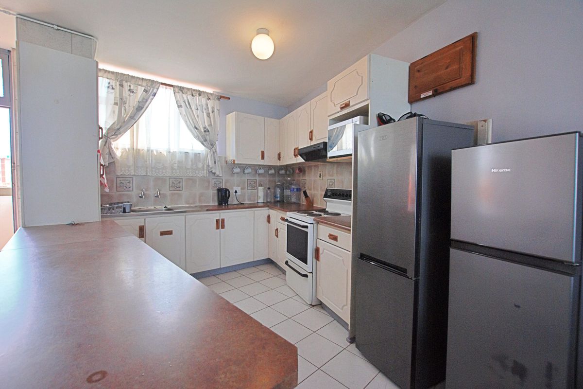 A functional kitchen featuring white cabinetry, tiled backsplash, laminate countertops, and tiled flooring, providing a practical layout for daily meal preparation.