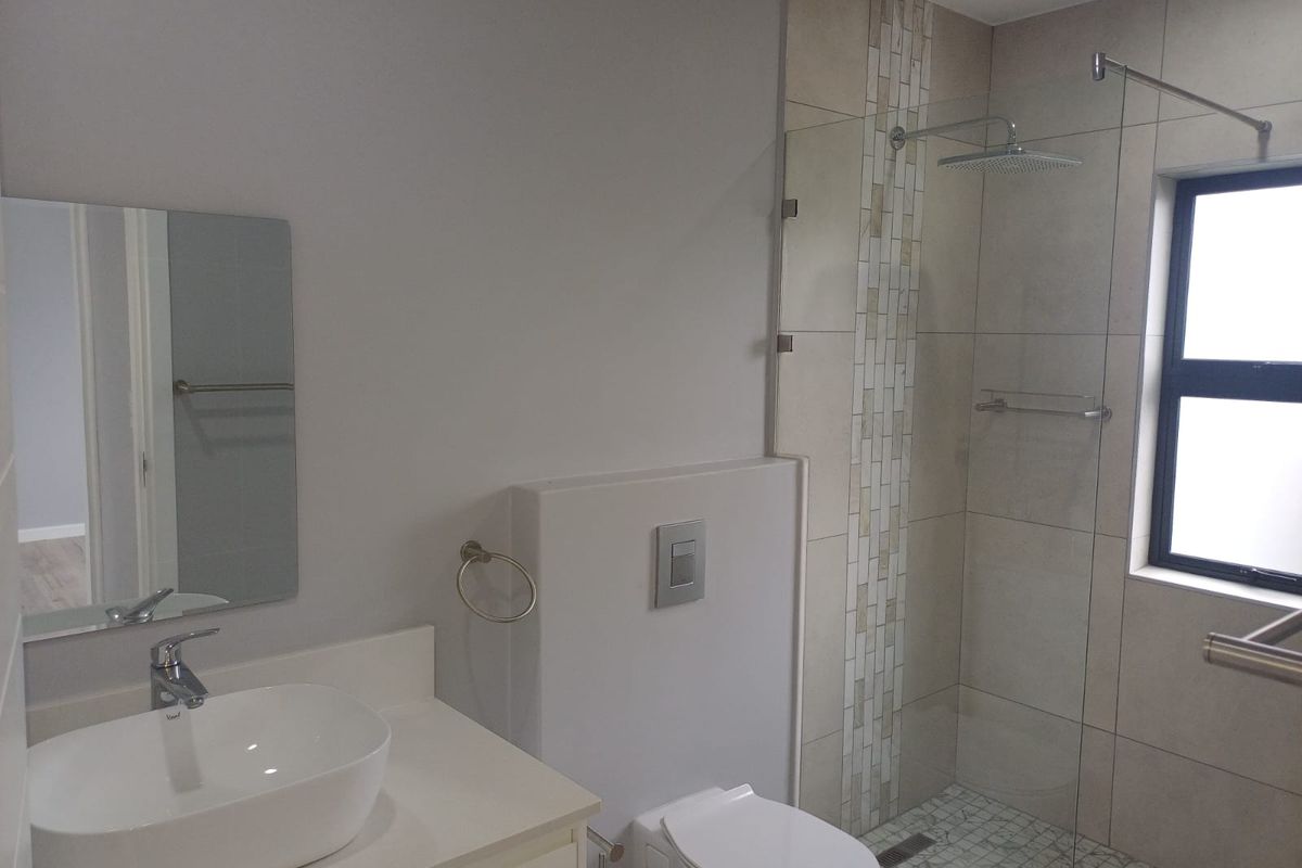 Modern bathroom featuring a vessel sink, concealed cistern toilet, and a spacious walk-in shower with a rain shower head and mosaic tile flooring.