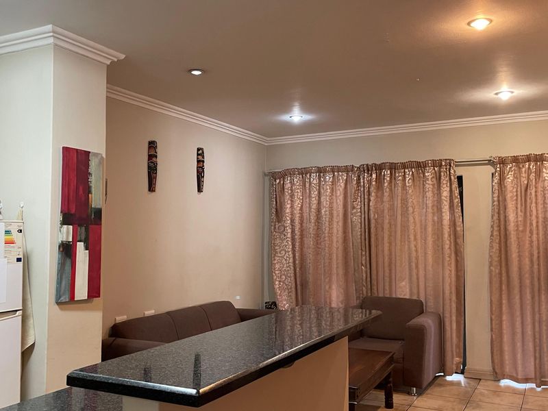 Open-plan living area featuring a granite breakfast bar, tiled flooring, and recessed downlighting, creating a functional space for dining and relaxation.