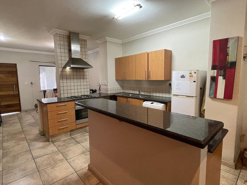 Functional kitchen featuring granite countertops, wooden cabinetry, built-in oven, hob, extractor fan, and a convenient breakfast bar for casual dining.
