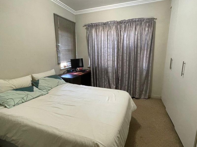 A functional bedroom featuring built-in cupboards, neutral wall finishes, and window treatments, offering a practical space for rest.