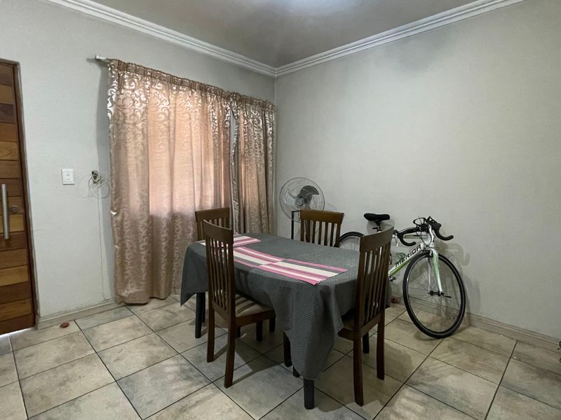 A dining room featuring tiled flooring, a solid wooden door, and decorative ceiling cornicing.