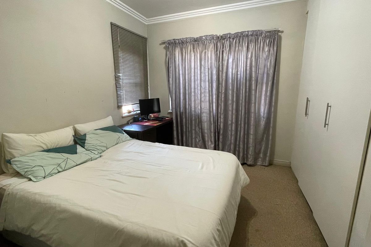 A functional bedroom featuring built-in cupboards, neutral wall finishes, and window treatments, offering a practical space for rest.