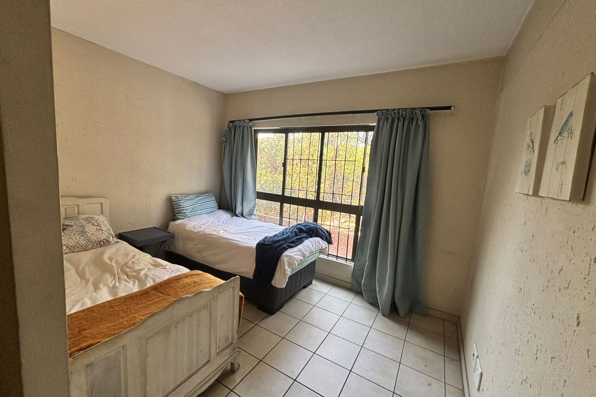 A bedroom featuring tiled flooring and a window with security bars, requiring cosmetic updates to the wall finishes.