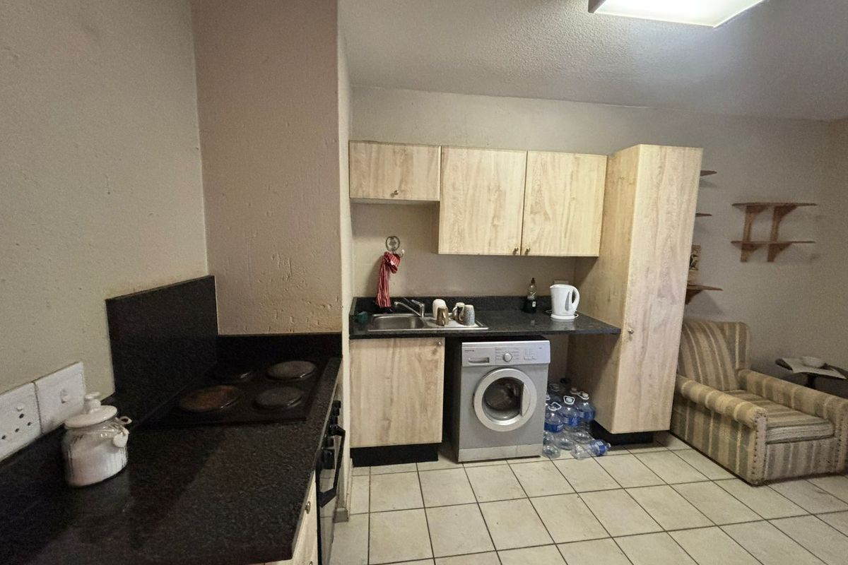 A functional kitchen area featuring built-in cabinetry, laminate countertops, an electric hob, and tiled flooring, offering a practical layout for daily use.