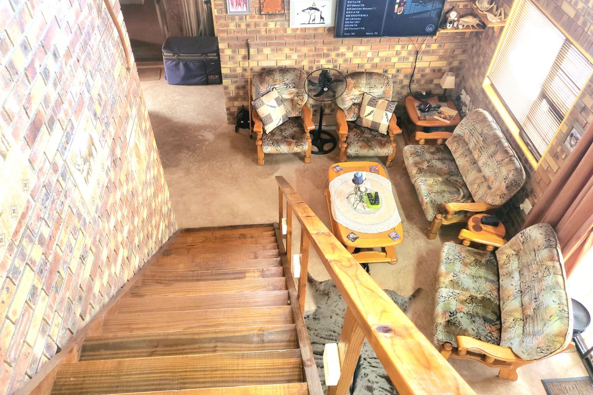 A living room area featuring exposed brick walls and a timber staircase with a wooden handrail, viewed from an elevated position.
