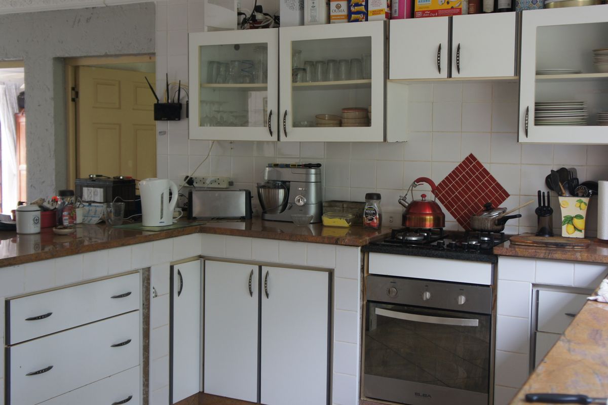 A functional kitchen featuring granite countertops, white cabinetry, and a built-in gas hob and oven, offering a practical layout for daily meal preparation.