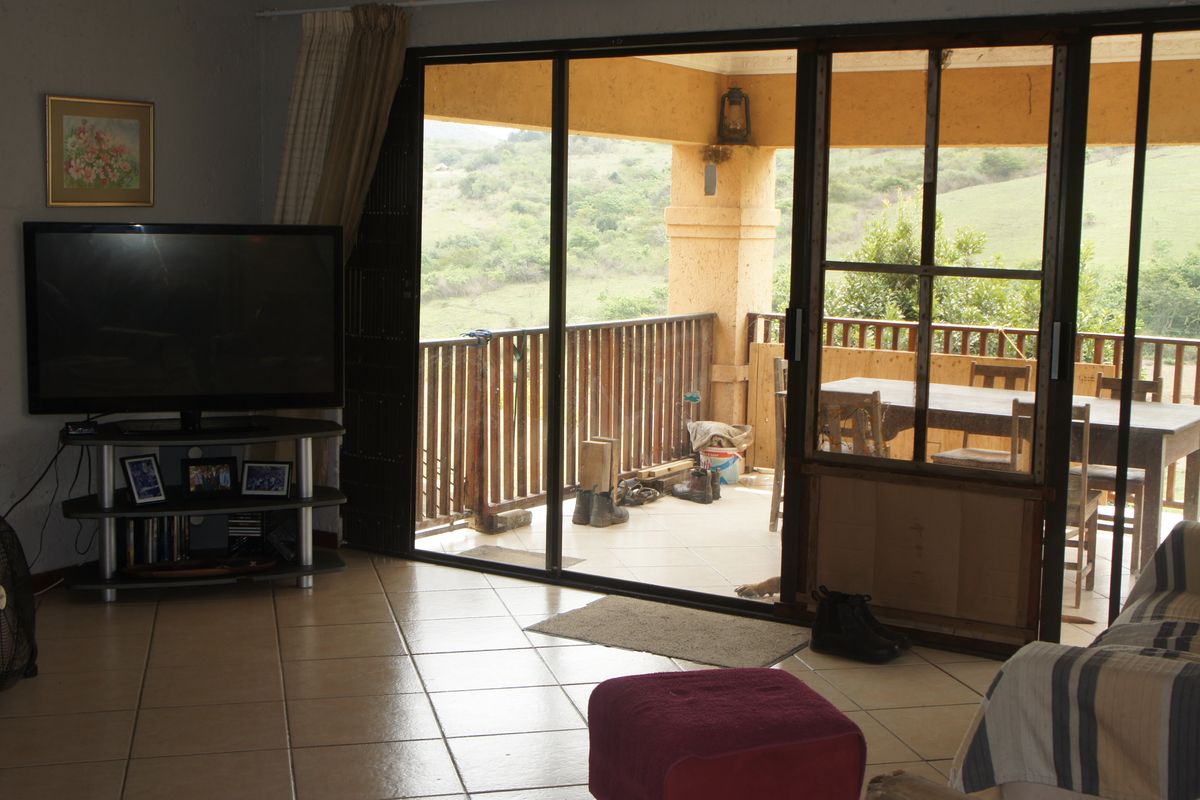 Living room with tiled flooring and large sliding glass doors opening onto a covered patio with scenic rural views.