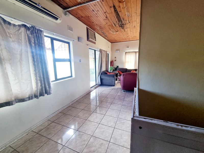 Living area featuring tiled flooring, timber ceiling with visible water damage, and sliding glass doors leading to the exterior.