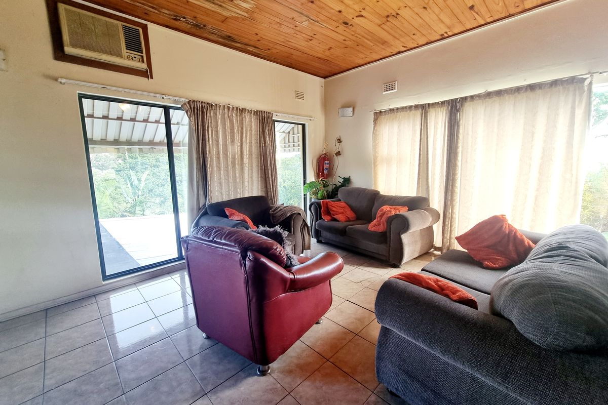 Spacious living room featuring ceramic tiled flooring, a timber-clad ceiling, and sliding glass doors providing access to the outdoor area.