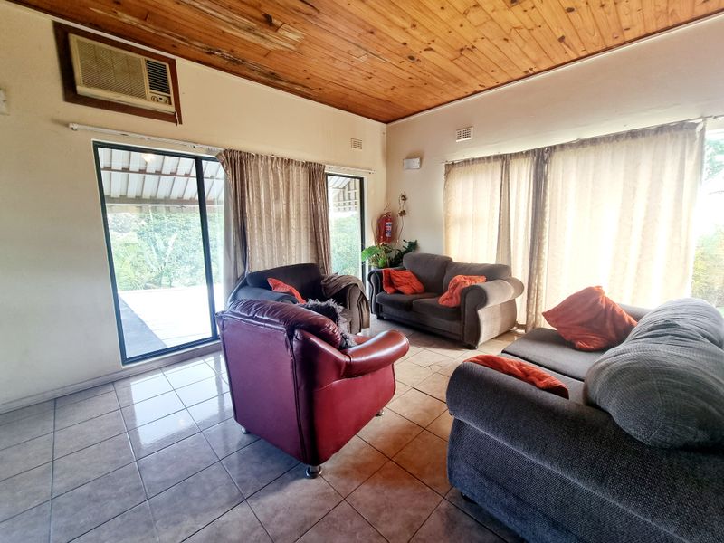 Spacious living room featuring ceramic tiled flooring, a timber-clad ceiling, and sliding glass doors providing access to the outdoor area.