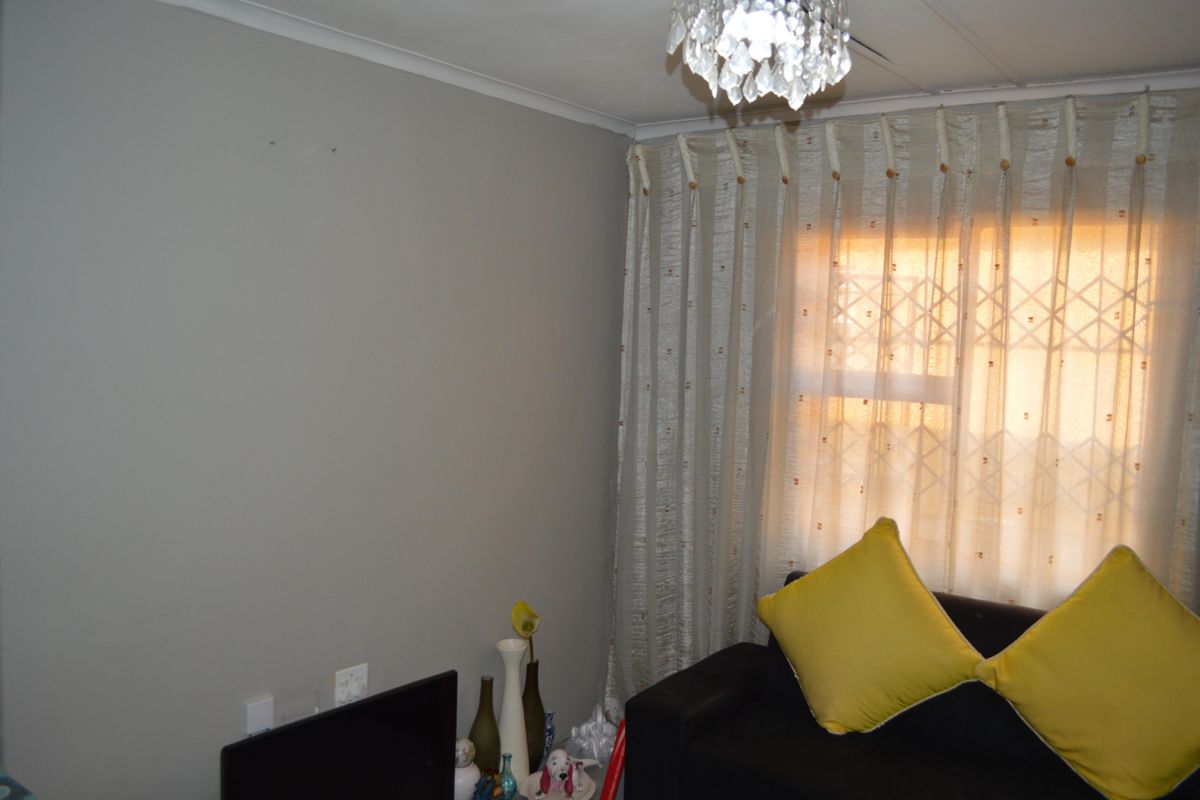A living room area featuring a window with a security gate and a decorative ceiling light fixture.