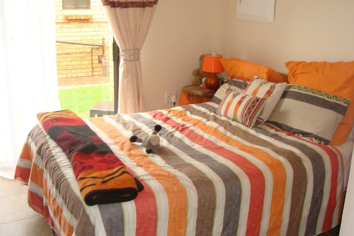 A bedroom featuring tiled flooring and a sliding glass door providing direct access to the exterior garden area.