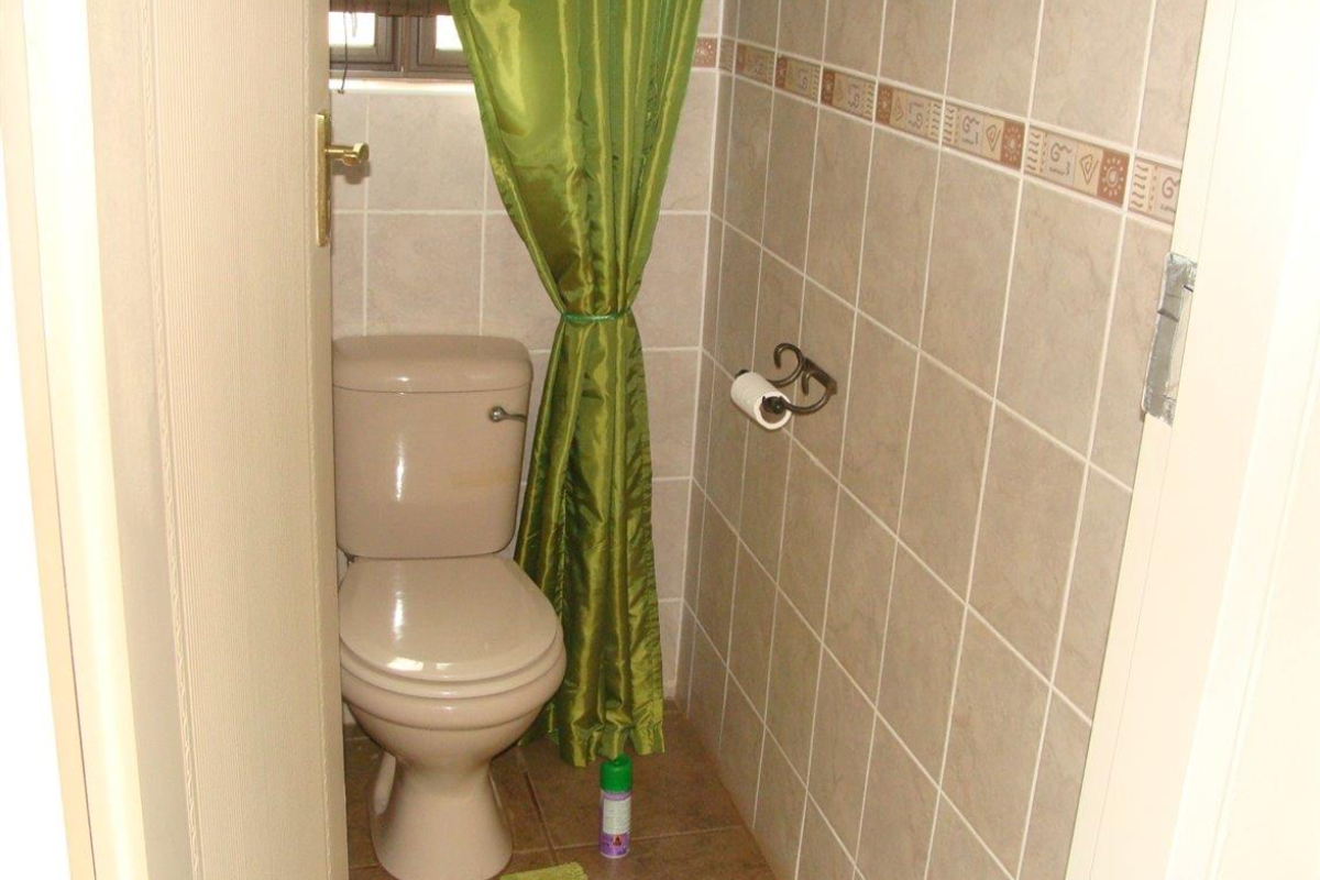 A compact guest bathroom featuring neutral ceramic wall tiles and a standard toilet suite.
