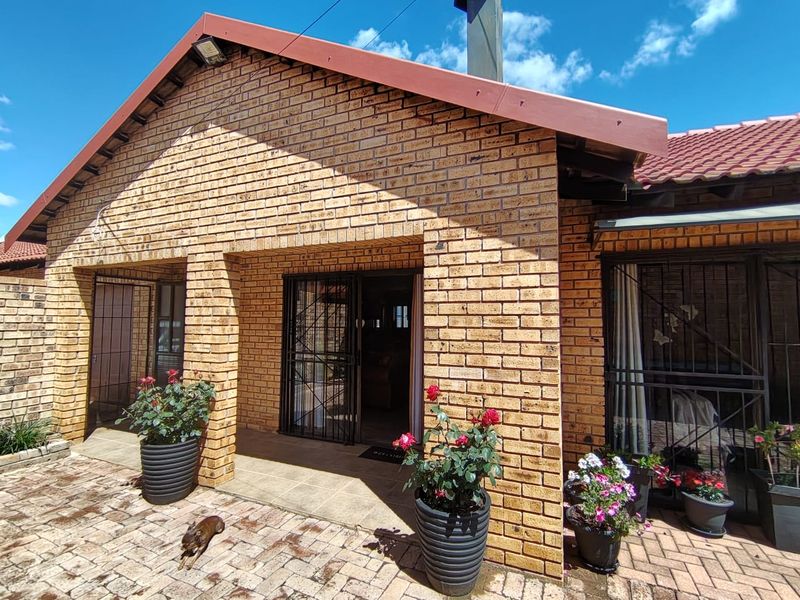 A covered patio area featuring face brick construction, tiled flooring, and secure metal gates, leading into the main living space.