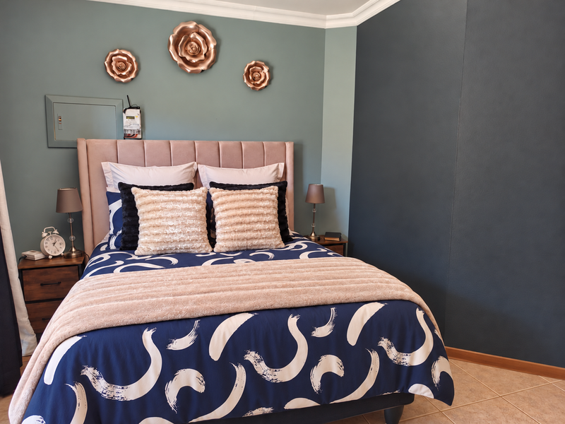 A well-maintained bedroom featuring tiled flooring, decorative coving, and a prominent feature wall with an integrated electrical distribution board.