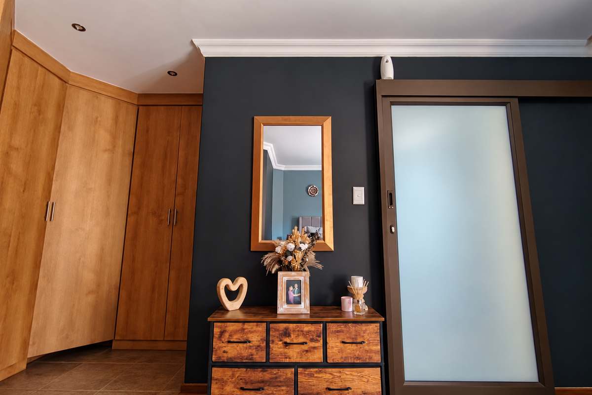 A well-maintained bedroom featuring built-in wooden cabinetry, a modern sliding frosted glass door, and elegant crown molding with recessed lighting.