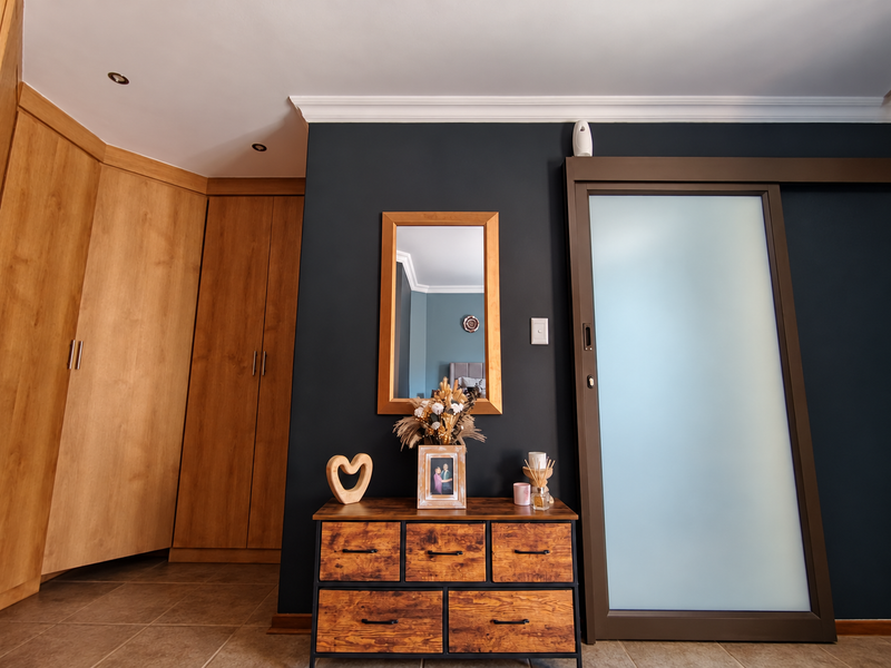 A well-maintained bedroom featuring built-in wooden cabinetry, a modern sliding frosted glass door, and elegant crown molding with recessed lighting.