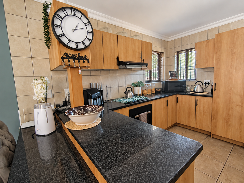 A functional kitchen featuring wooden cabinetry, granite countertops, a built-in oven, and a tiled backsplash, offering a practical and well-maintained workspace.