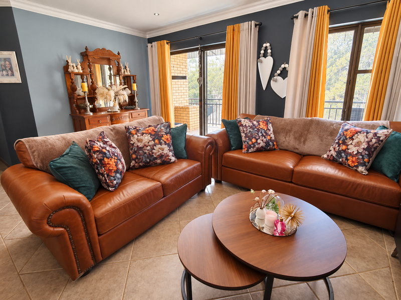 A well-maintained living room featuring tiled flooring, crown molding, and large sliding glass doors that provide access to an outdoor area.